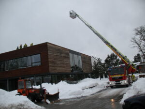 Mehrere Freiwillige Feuerwehren sind im Einsatz, um das Dach der Schule vom Schnee zu befreien. (Foto: Erhard)